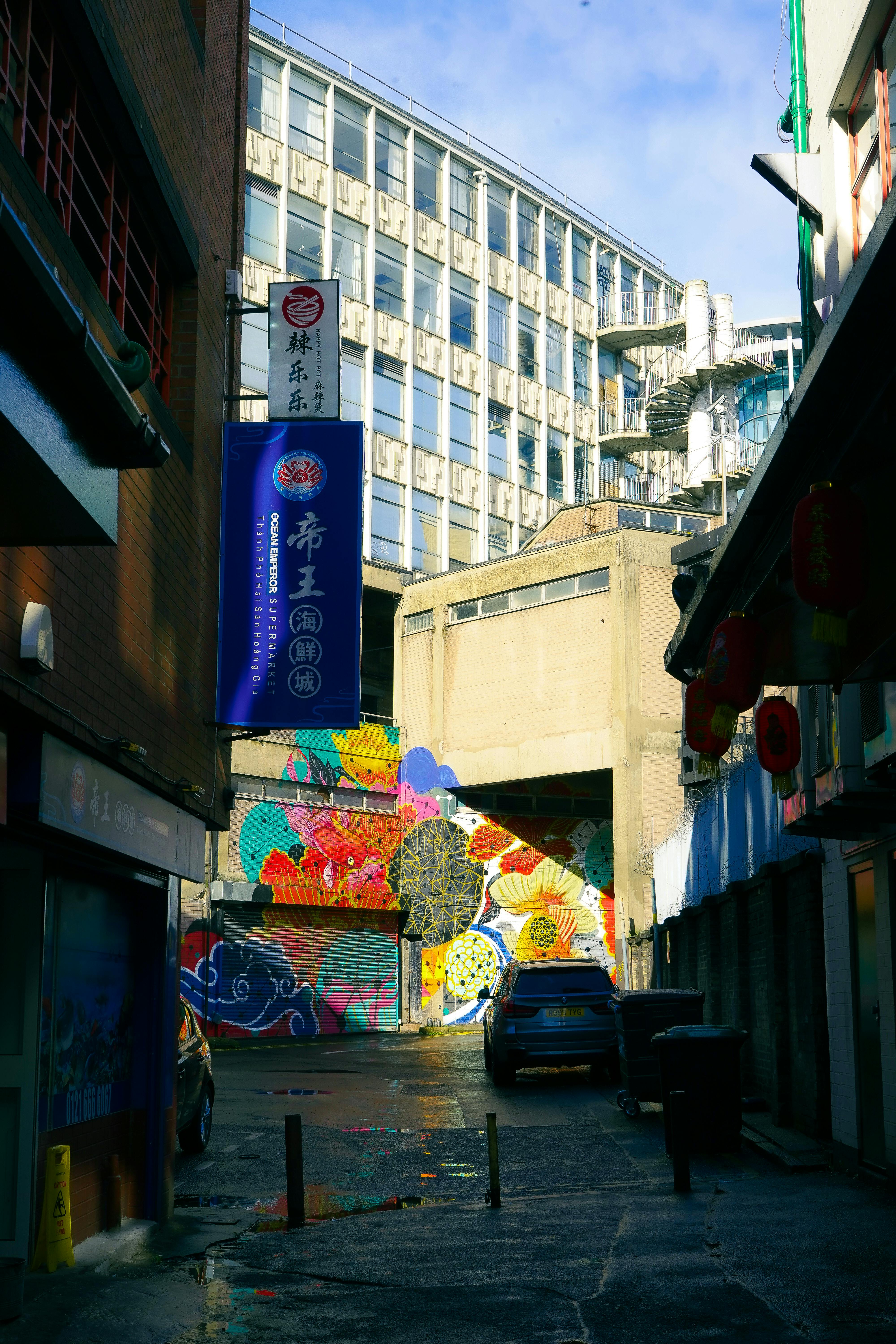 Colorful mural in a Birmingham alleyway with modern architecture and cultural charm.
