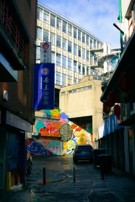 Colorful mural in a Birmingham alleyway with modern architecture and cultural charm.