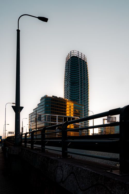 Free A modern skyscraper reflecting sunlight, captured at dusk with an urban cityscape. Stock Photo