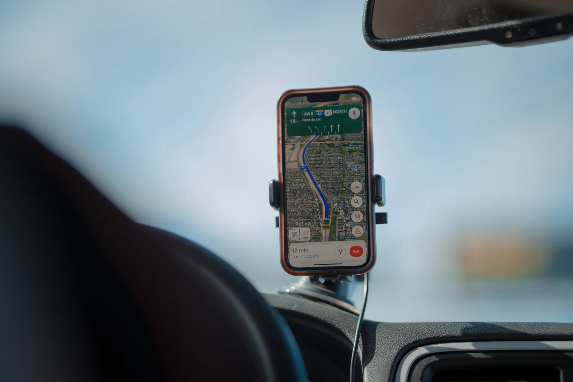 A phone running navigation mounted on a car dashboard on an open road A phone running navigation mounted on a car dashboard on an open road