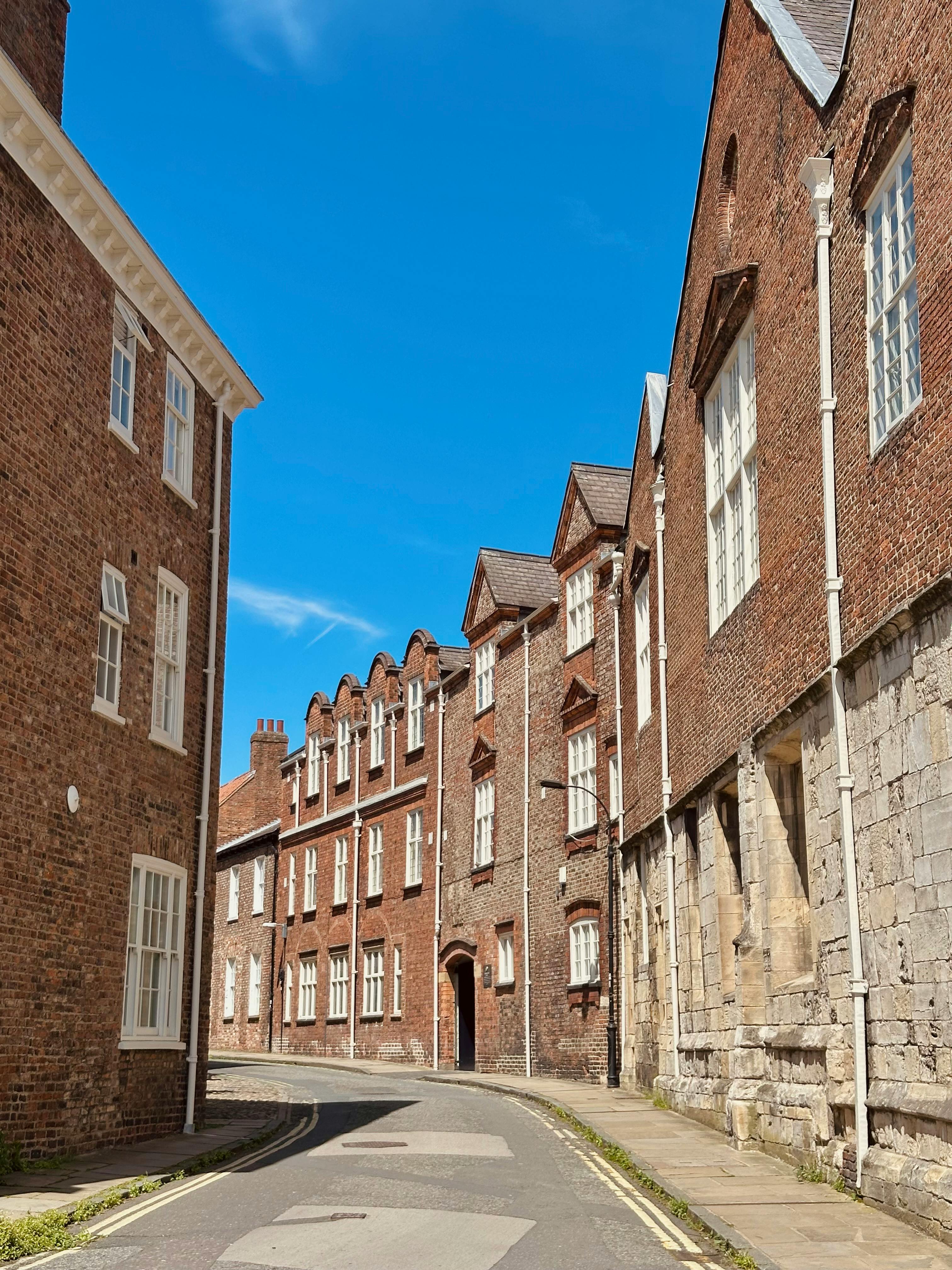 Captured on a sunny day, this classic York street scene features historic brick architecture under a vibrant blue sky.