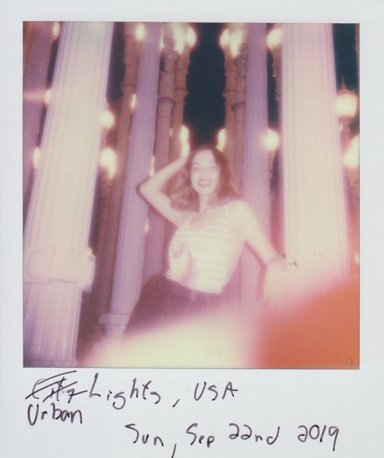 Smiling woman poses at night in front of Urban Lights installation.