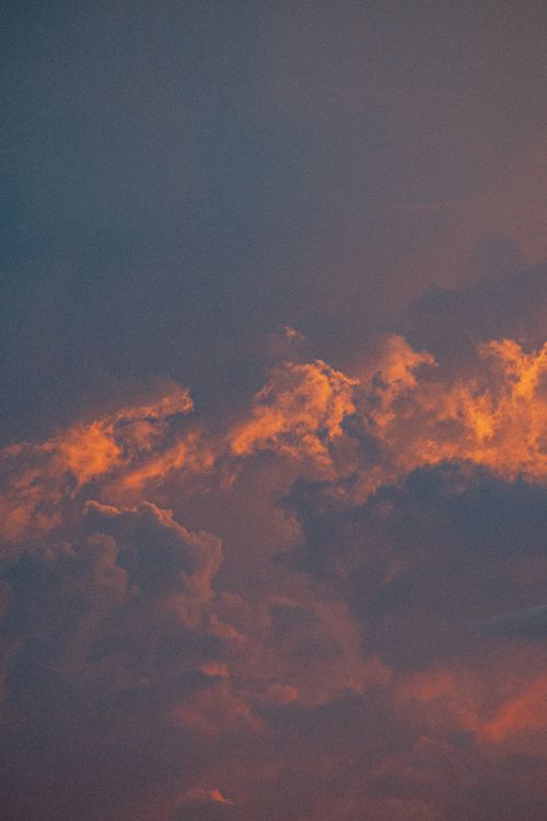 Free Vibrant orange and blue clouds at sunset create a dramatic evening sky. Stock Photo