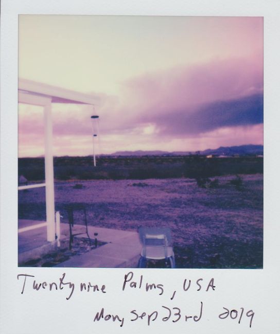 Retro Polaroid photo capturing a tranquil desert scene in Twentynine Palms, USA, with a purple-hued sky.