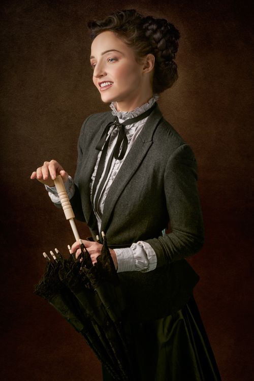 Free Elegant woman in vintage attire holding an umbrella with a smile. Stock Photo