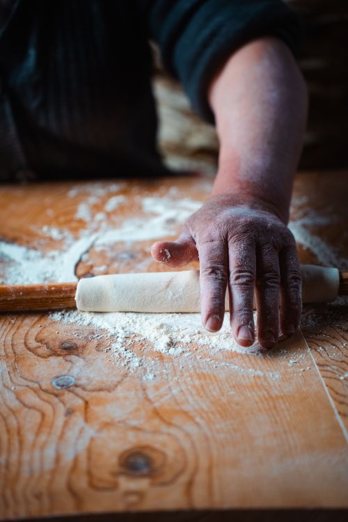 Free Hand rolling dough with flour dust on wooden table, capturing authentic breadmaking in Antalya, Türkiye. Stock Photo