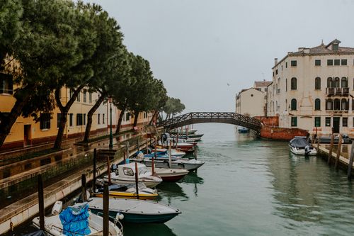 Free Scenic view of a vibrant canal in Venice featuring boats, trees, and historic architecture. Stock Photo