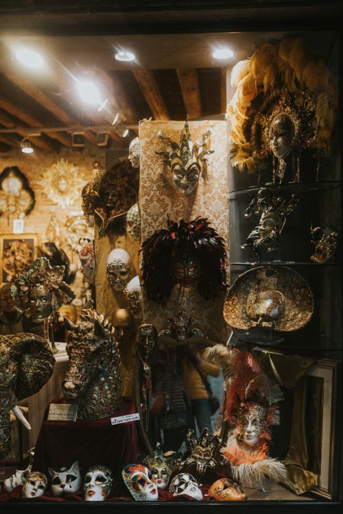 Free Explore the charm of Venetian masks with this artistic display in a dimly lit shop window. Stock Photo