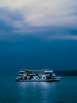 Serene boat cruising on calm waters under a twilight sky in Panaji, India.