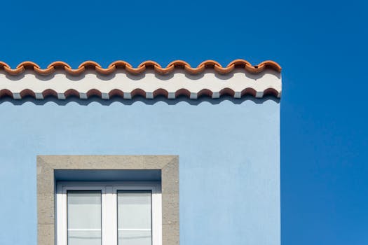 Bright blue house facade with distinctive orange roof tiles under a clear sky.