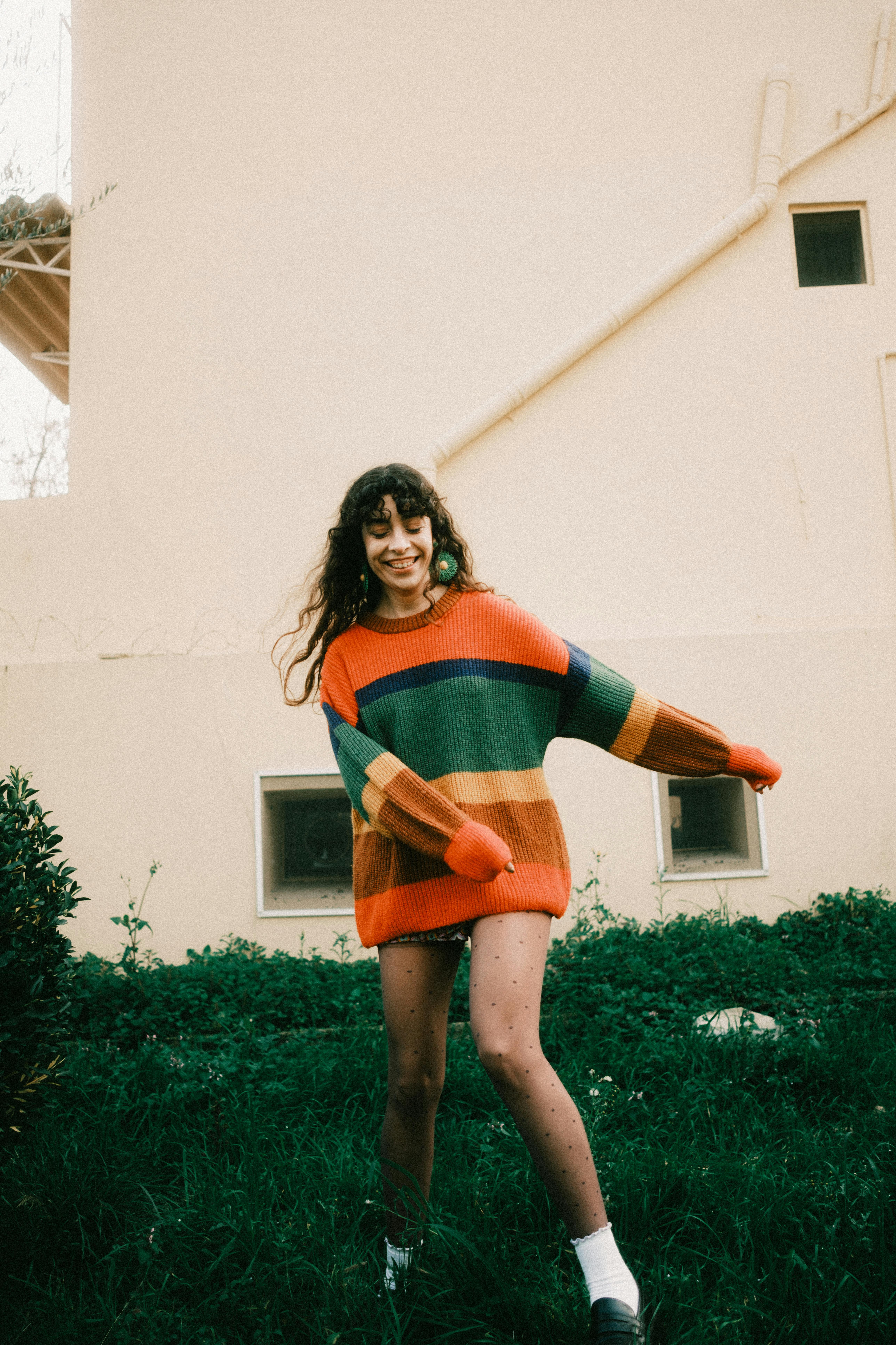 Young woman in striped colorful sweater enjoying a walk outdoors, radiating joy and style.