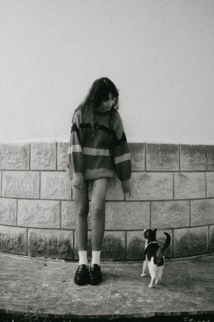 Artistic black and white photograph of a girl and a cat outdoors.