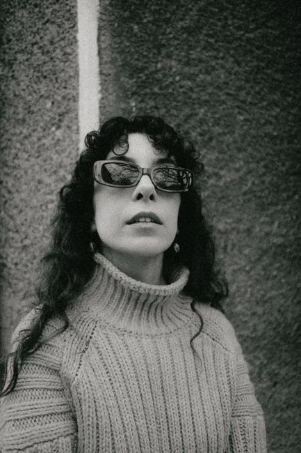 Stylish black and white portrait of a woman wearing sunglasses and a woolen sweater.