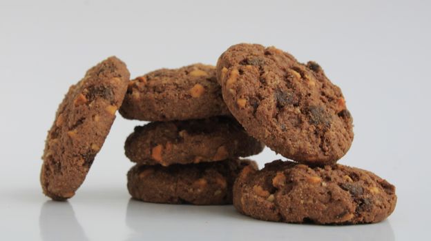 Close-up of six chocolate cookies stacked on white surface, perfect for any snack.