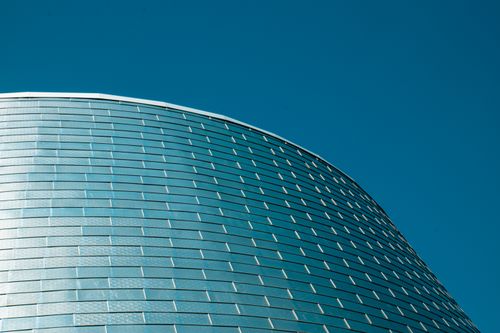 Free Elegant curved glass facade of modern building against clear blue sky in Montreal, Canada. Stock Photo