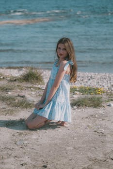 A serene portrait of a woman in a blue dress on a beach, radiating calmness and style.