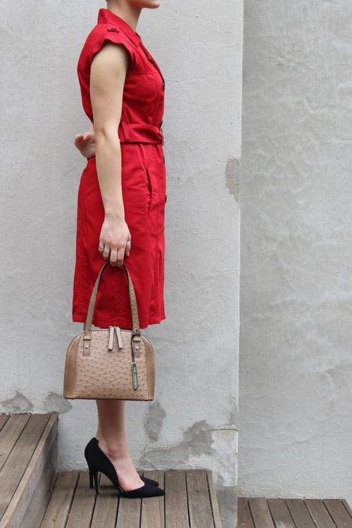 Free Fashion-forward woman in red dress holding a beige handbag, showcasing chic style. Stock Photo