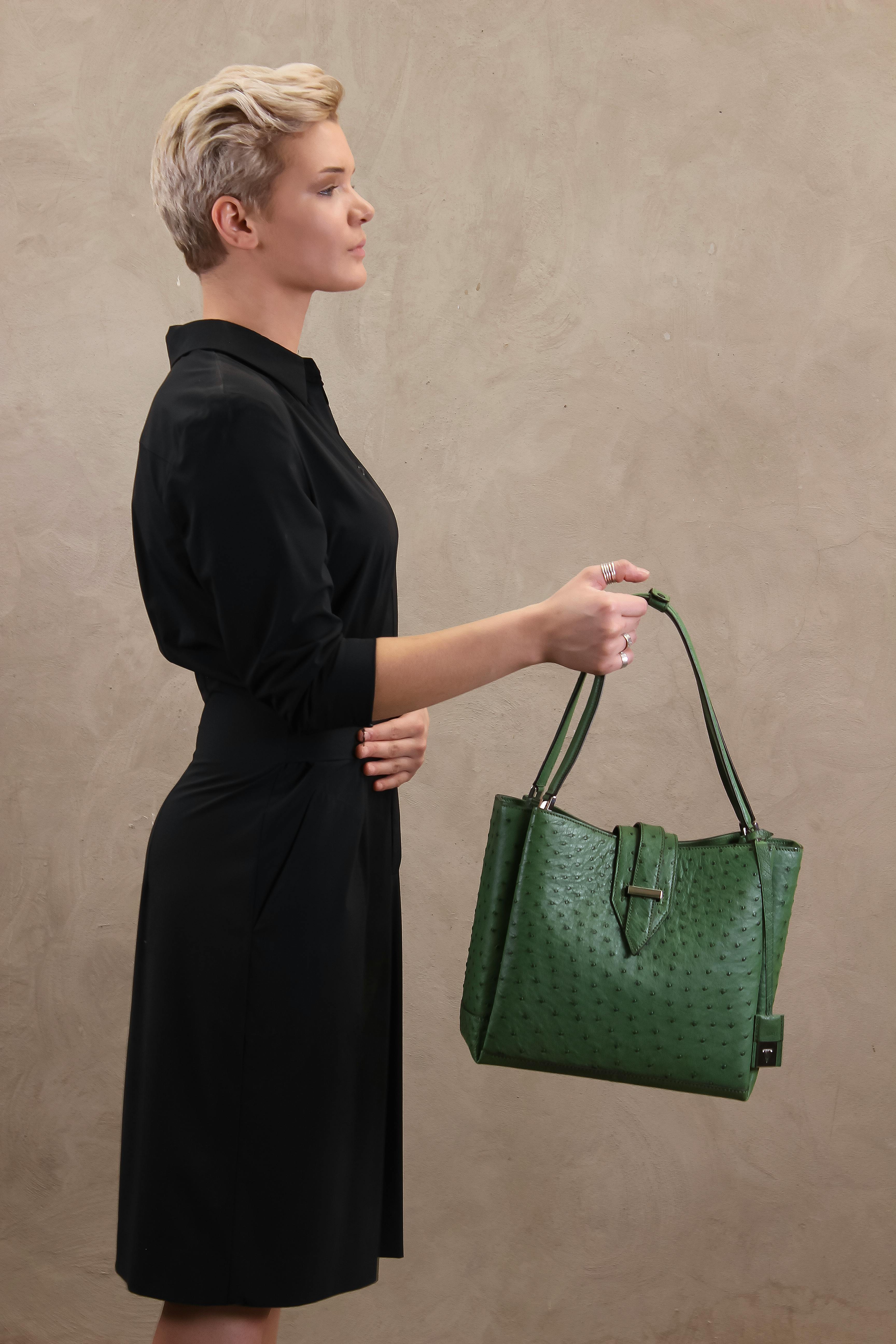 Profile of a stylish woman holding a green handbag, showcasing modern fashion elegance.