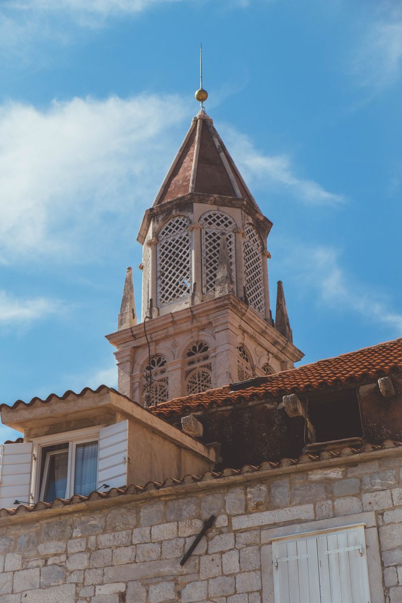 A striking historic bell tower against a blue sky in Split-Dalmatia County, Croatia.