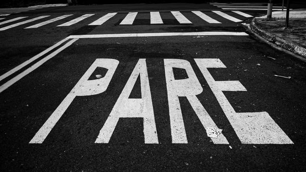 Black and white image of 'PARE' on a street in Hortolândia, Brazil.