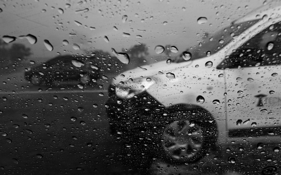 Black and white view through a rainy window at Mar del Plata, Argentina, capturing cars in motion.