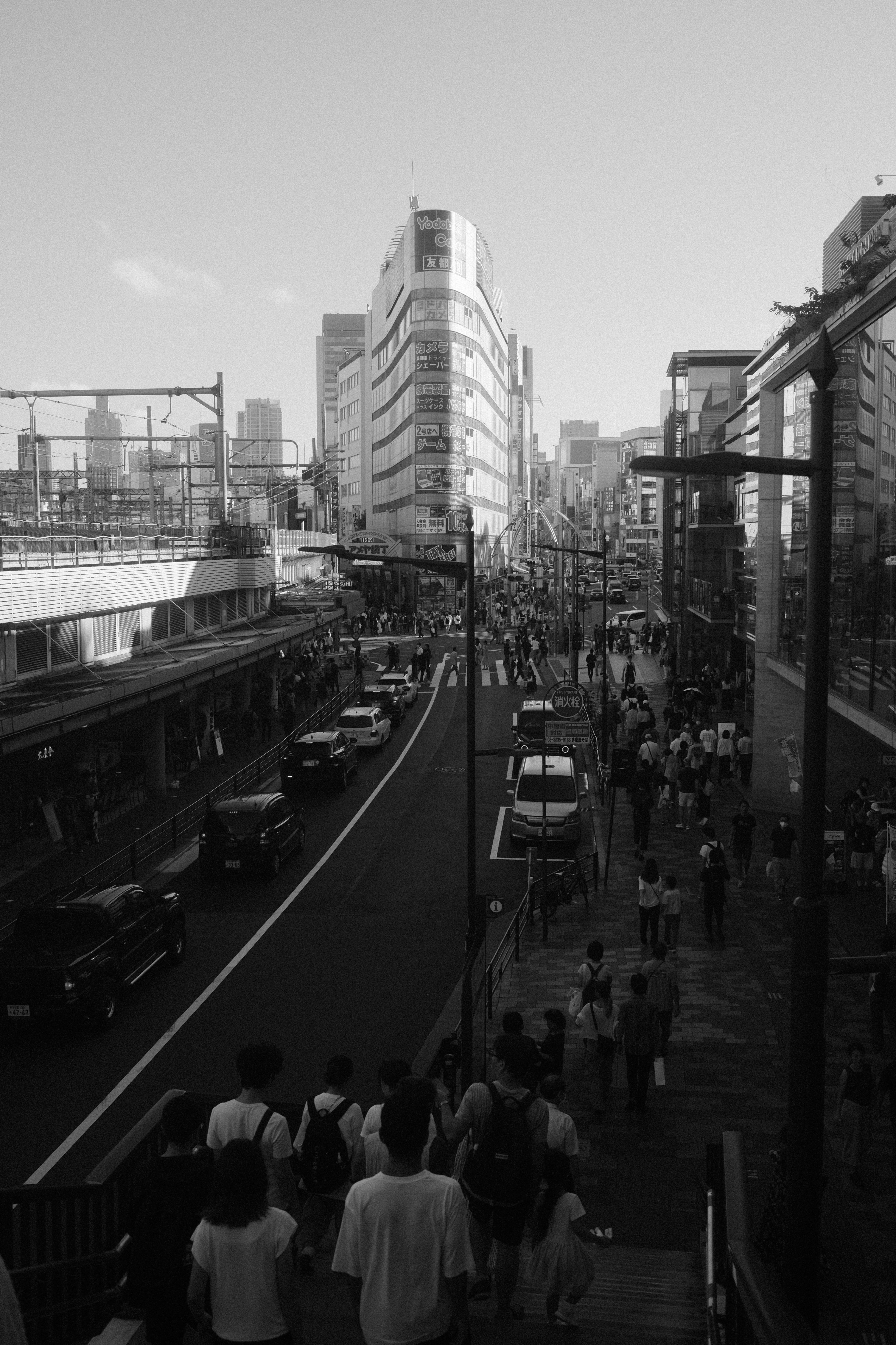 Black and white photo of bustling Tokyo street with crowds and modern buildings.