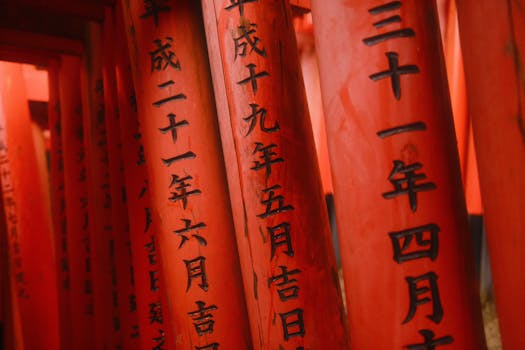 Close-up of traditional red torii gates with Japanese calligraphy in Kyoto, Japan.