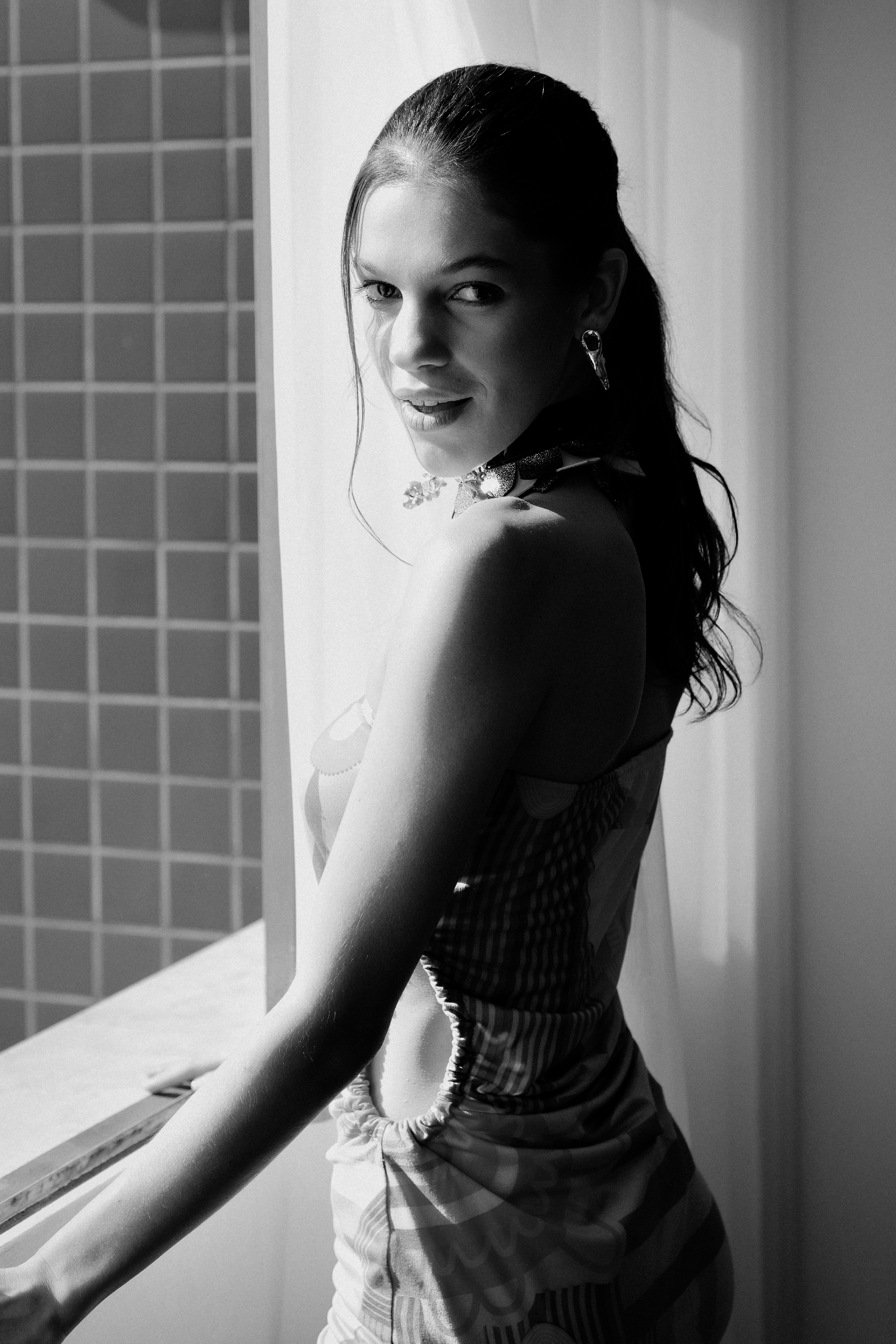 Stylish black and white portrait of a woman by a window in Belo Horizonte.