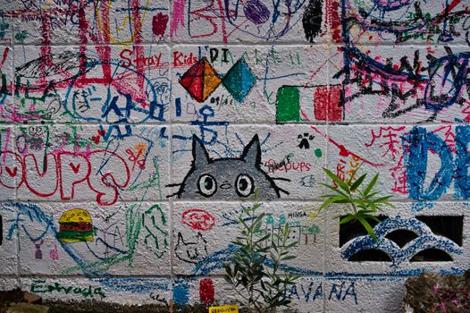 A vibrant graffiti wall in Tokyo with colorful illustrations and plants.