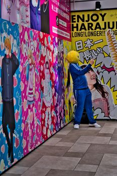 A cosplayer in Harajuku, Tokyo, poses against colorful anime-themed walls, embodying pop culture vibrancy.