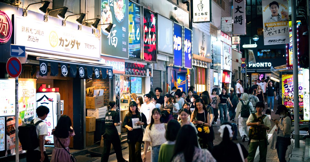 Busy street in Shibuya, Tokyo at night, showcasing neon signs and bustling crowds.