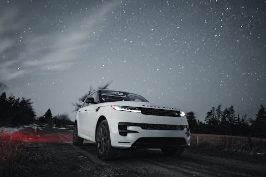 White luxury SUV on a scenic route under a star-filled night sky, capturing adventure and elegance.