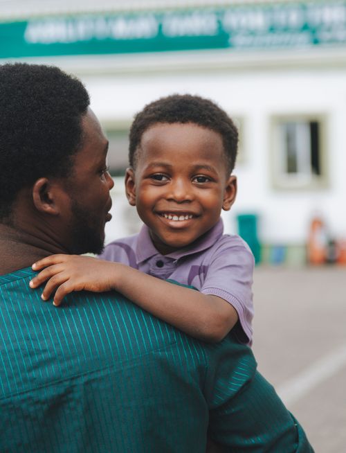 Free Smiling child embracing father outdoors, capturing joy and bonding. Stock Photo