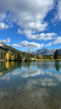 Scenic view of a serene mountain lake reflecting the vibrant autumn colors under a clear blue sky.