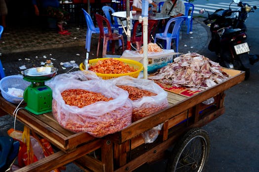 Wooden cart at vibrant market displaying dried seafood, street food scene.