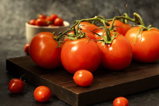 A close-up shot of fresh vine tomatoes on a rustic wooden board, showcasing their vibrant red color.