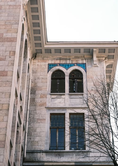 Free Close-up view of a historic building's arched windows and stone facade, showcasing architectural details. Stock Photo