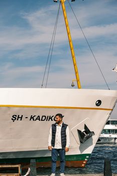 A man stands by a large ship under a clear blue sky, showcasing maritime travel. - Fotografer Sidoarjo