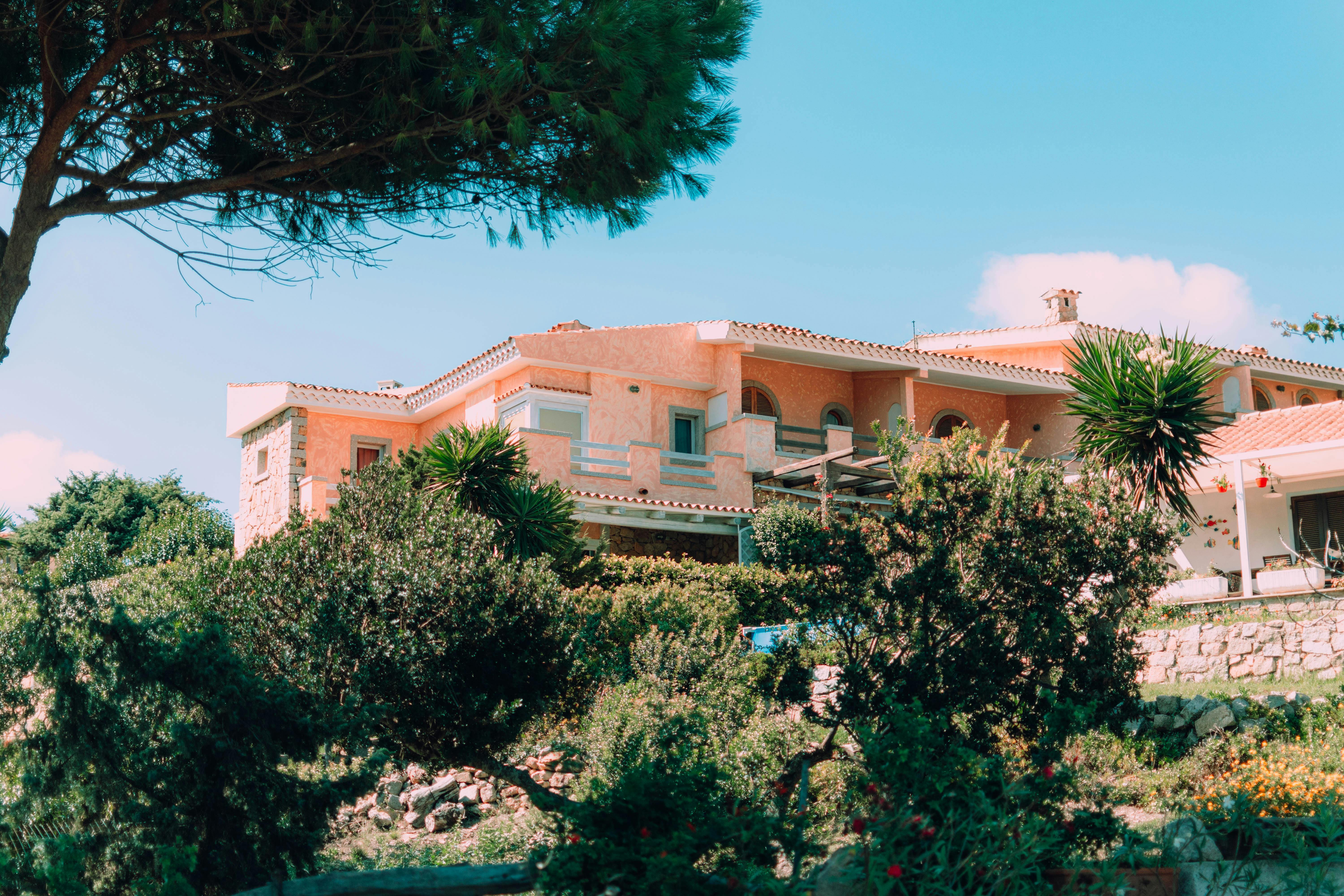 Charming Mediterranean villa nestled in vibrant, lush gardens under a clear blue sky.