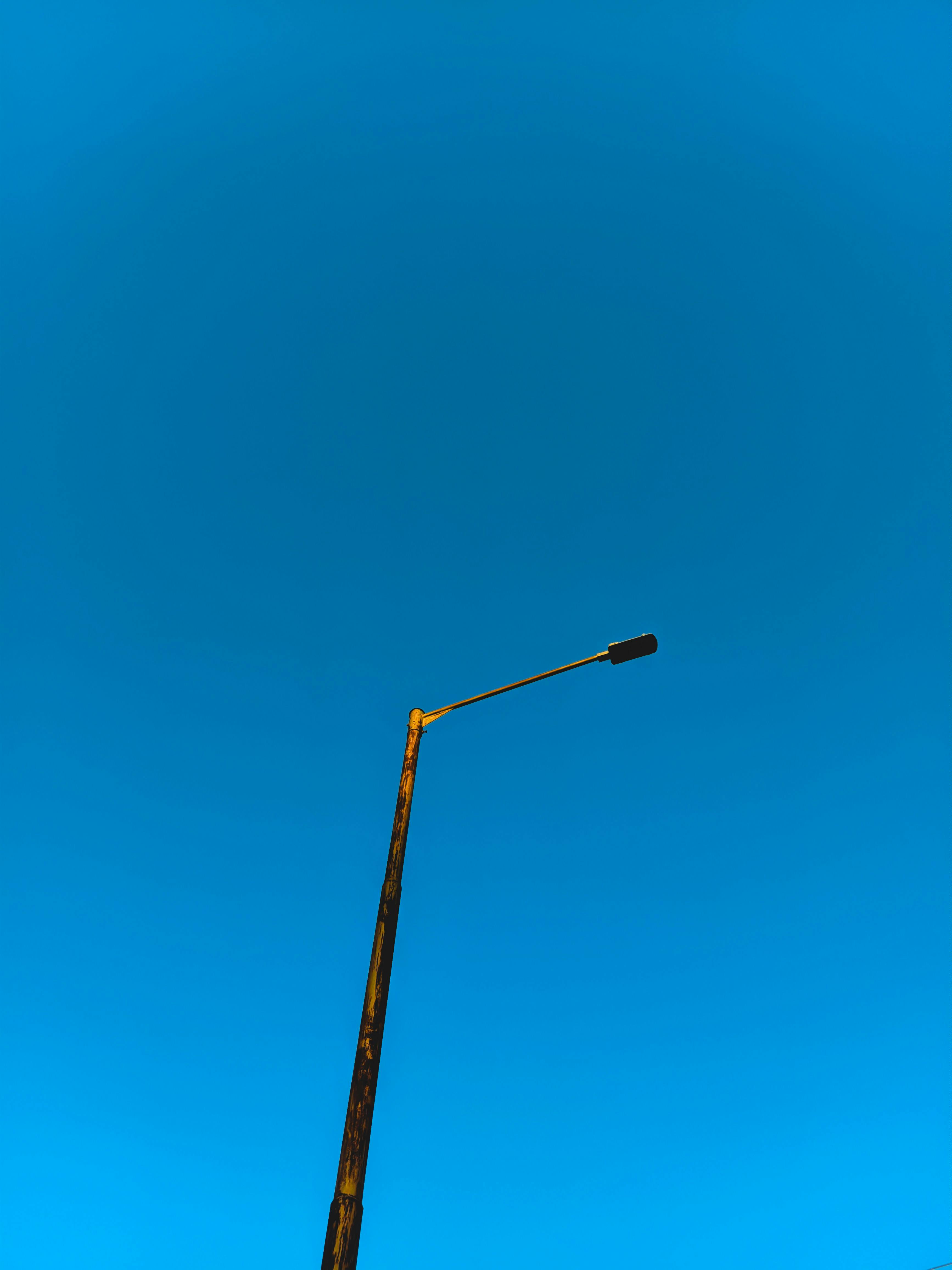 Gratuit Un lampadaire solitaire se dresse fièrement sur un ciel bleu vibrant, capturant le minimalisme. Photos