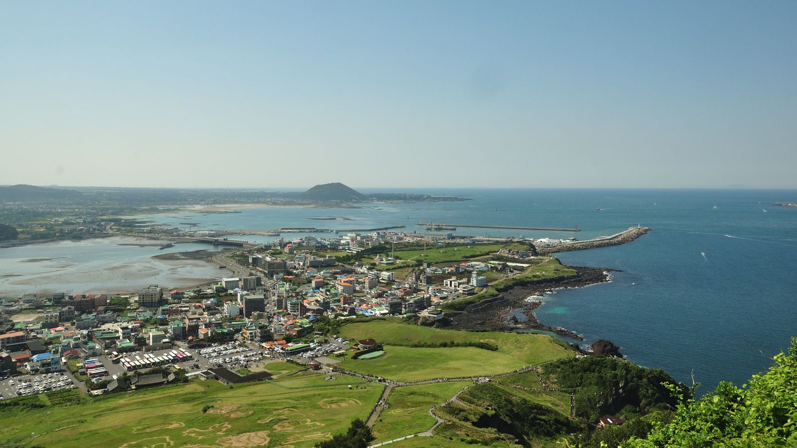 A breathtaking aerial view of Jeju Island's coastline, showcasing the vibrant city and blue ocean.
