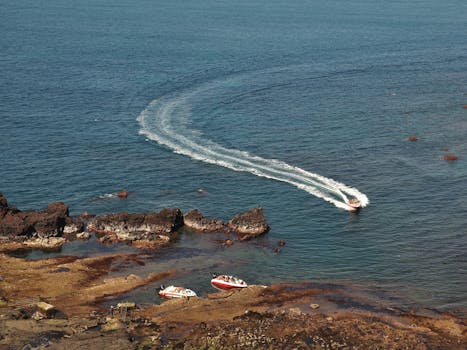 A speedboat creating waves by a rocky shoreline in South Korea. Scenic and serene seascape.