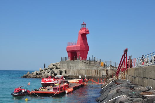 A unique red horse-shaped lighthouse on a coastal pier in South Korea, under clear blue skies.
