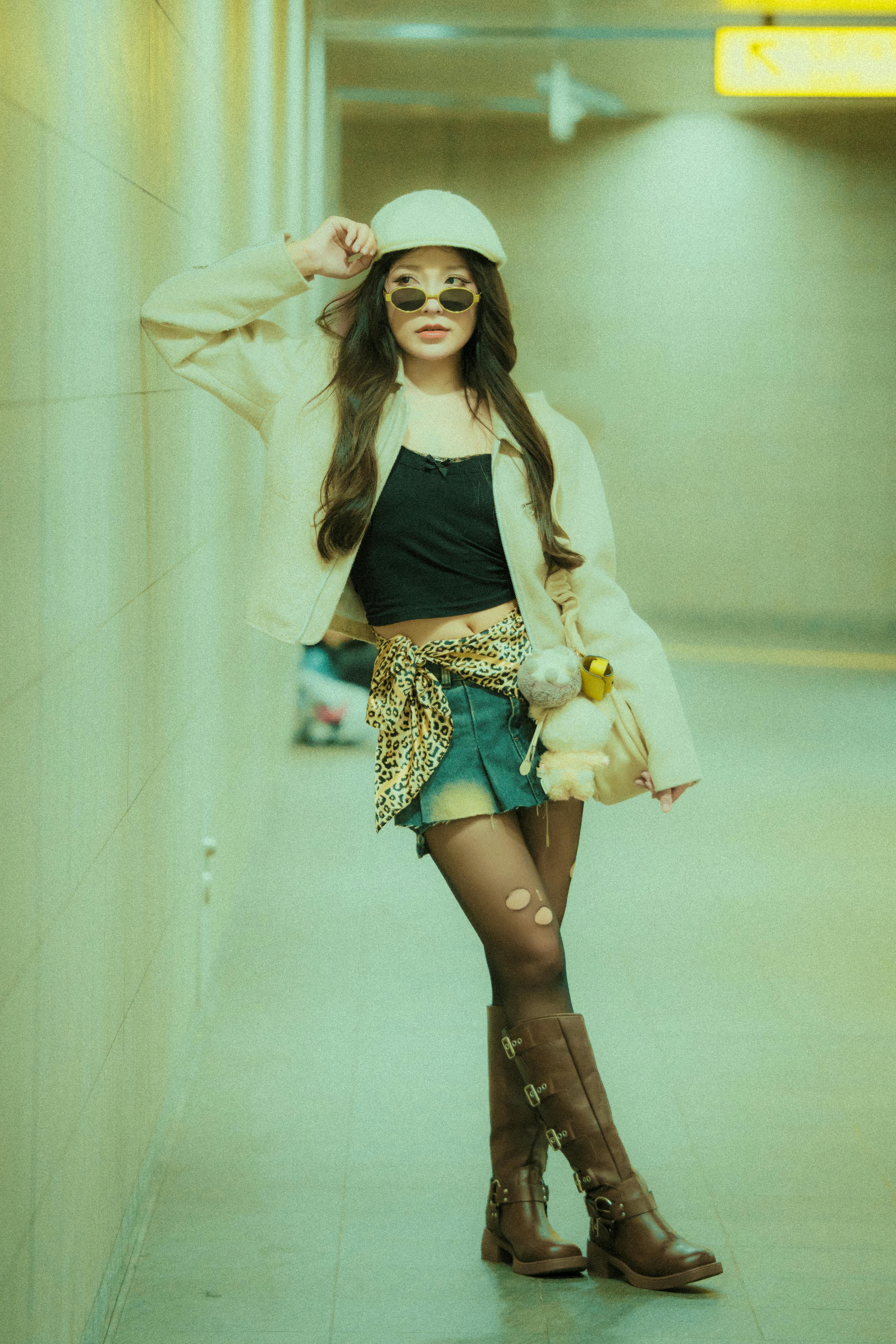 Fashionable young adult in chic outfit posing confidently in a subway corridor.