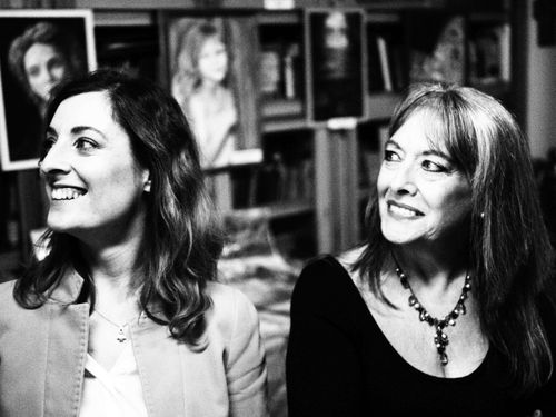 Free Black and white portrait of two smiling women indoors with art in the background. Stock Photo