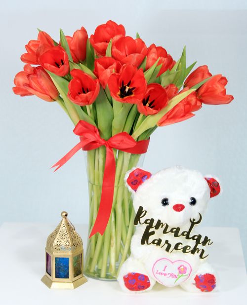Free Bright red tulips with Ramadan-themed teddy and lantern create a joyful festive arrangement. Stock Photo