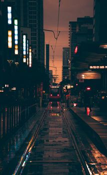 Moody urban night scene with a train arriving at a city station amid vibrant lights.