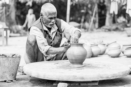 Free Elderly artisan shaping a clay pot at an outdoor pottery wheel in India. Stock Photo