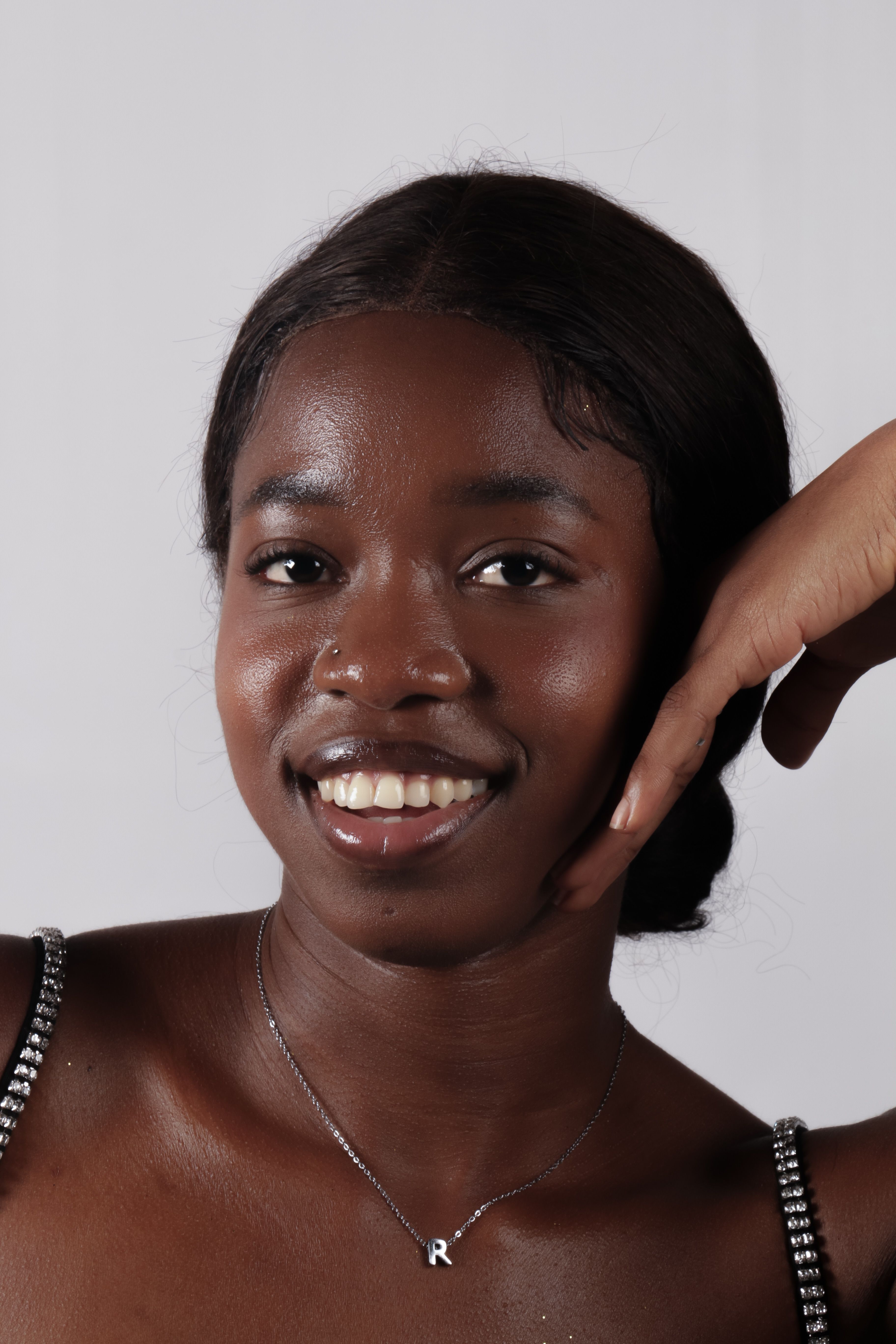 Close-up portrait of a smiling young woman with a calm expression and elegant jewelry.