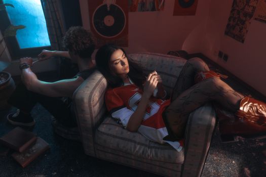 Two young adults relaxing on a couch in a retro-styled room, ambient lighting.